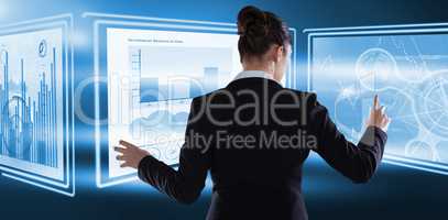 Composite image of rear view of businesswoman using imaginative digital screen