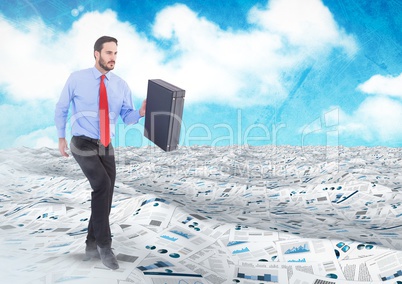 Businessman holding briefcase in sea of documents under sky clouds