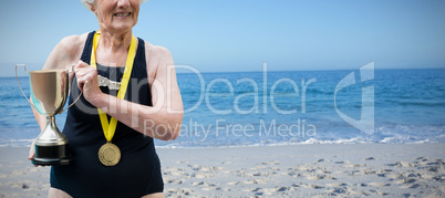 Composite image of portrait of confident swimmer showing trophy