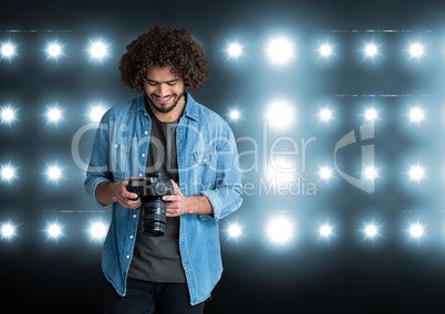 young photographer looking the photos on the camera. Stadium lights behind