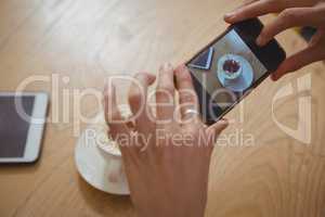 Cropped hands of woman photographing coffee cup