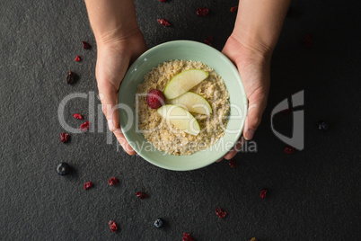 Hands holding a bowl of fruit cereal