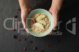 Hands holding a bowl of fruit cereal