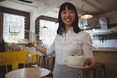 Portrait of waitress holding coffee cups at cafe