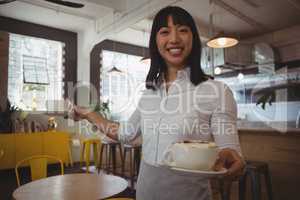 Portrait of waitress holding coffee cups at cafe