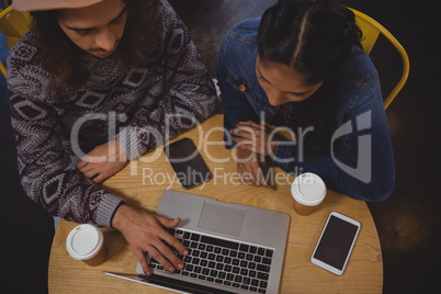 High angle view of friends using laptop in cafe