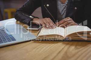 Mid section of woman with book in cafe