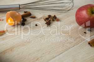 High angle view of spices and apple with wire whisk