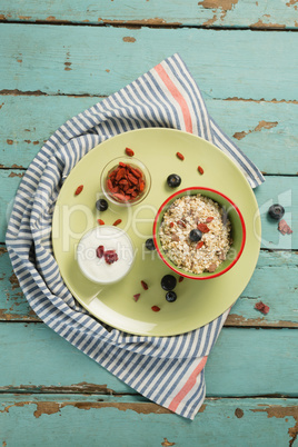 Plate of breakfast cereal with fruits and yogurt on wooden table