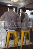 Rear view of couple on stools in cafe
