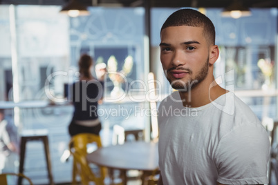 Portrait of man with friend in background at cafe