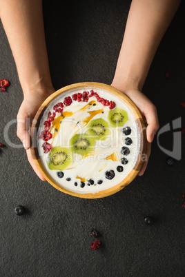 Hands holding a bowl of fruit cereal