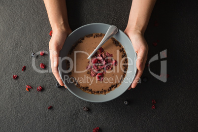 Hands holding a bowl of fruit cereal