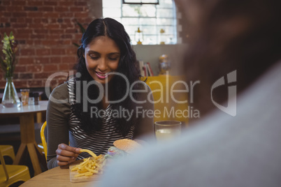 Woman with friend having French fries in cafe