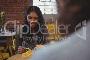 Woman with friend having French fries in cafe