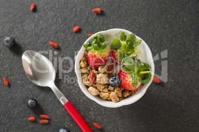 Bowl of breakfast cereals and fruits with spoon