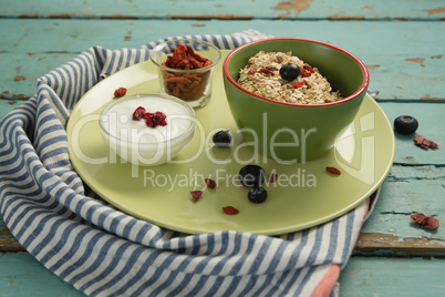 Plate of breakfast cereal with fruits and yogurt on wooden table