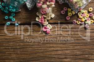 Scattered honeycomb cereals from jar on wooden table