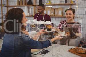 Owner serving muffin and coffee to customer