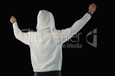 Female athlete in hooded jacket standing with arms raised