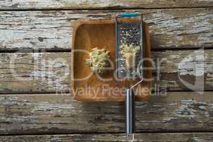 Overhead view of steel grater and ginger in plate on table