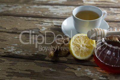 High angle view of fresh honey and lemon with ginger tea on weathered table