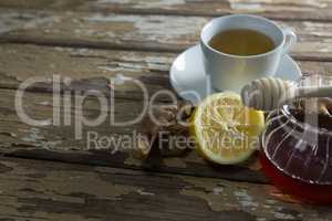 High angle view of fresh honey and lemon with ginger tea on weathered table