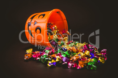 Bucket with chocolates during Halloween over black background