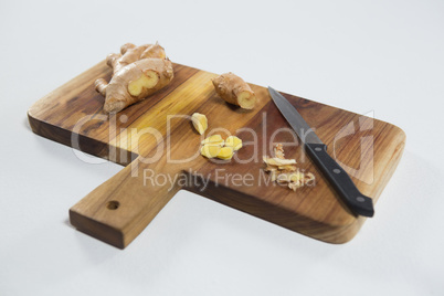 High angle view of knife and fresh ginger on wooden cutting board