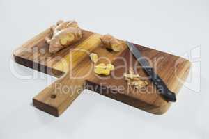 High angle view of knife and fresh ginger on wooden cutting board