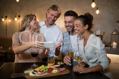 Group of friends reviewing pictures on mobile phone