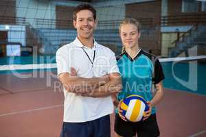 Happy male coach and volleyball player standing in the court
