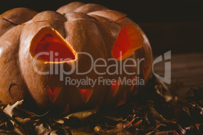 Close up of jack o lantern with leaves on table during autumn