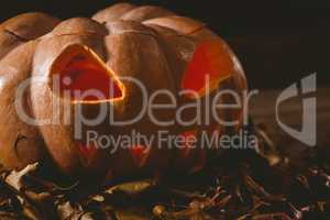 Close up of jack o lantern with leaves on table during autumn