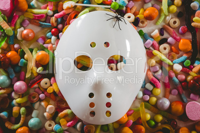 Mask with various candies over white background