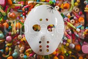 Mask with various candies over white background