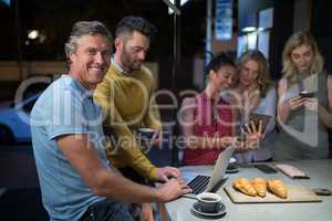 Friends using electronic gadgets while having coffee