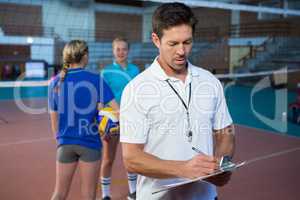 Male coach writing on clipboard