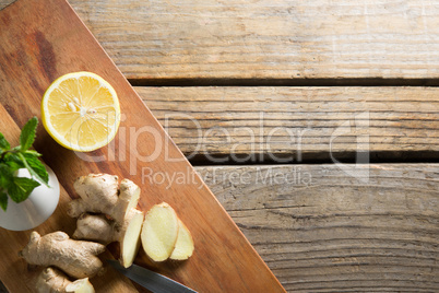 Overhead view of ginger with lemon on cutting board over table