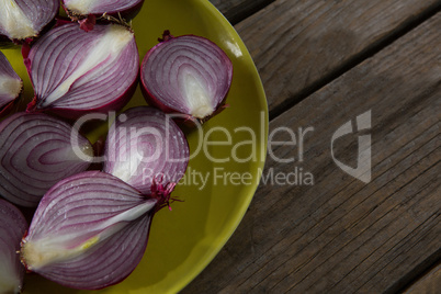 Halved onions in a plate on wooden table