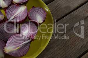 Halved onions in a plate on wooden table