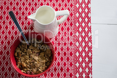 Bowl of wheat flakes with spoon and jug