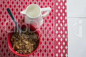 Bowl of wheat flakes with spoon and jug
