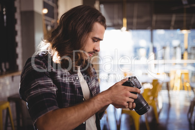 Side view of young male photographer holding DSLR camera