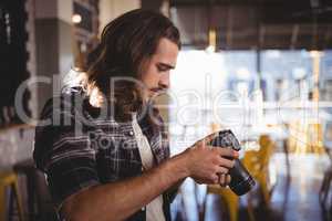 Side view of young male photographer holding DSLR camera