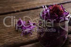 Chopped red cabbage in jar on wooden table