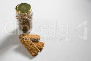 Granola bar and cereal in jar on white background
