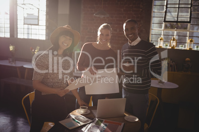 Portrait of smiling young creative team standing at coffee shop