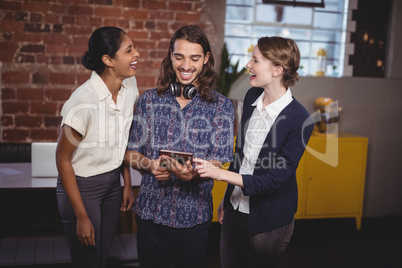 Cheerful young friends standing with digital tablet