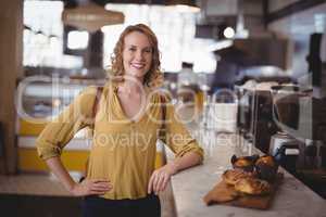 Portrait of smiling young female customer standing by counter